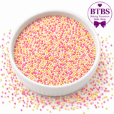BTBS Baking Treasures Bake Shop pink, yellow and white nonpareil sprinkle mix in a white bowl on a clean white background