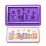 the word 'Babyland' in pastel block letters with small flag accents, on a white background.