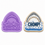 Two shark-mouth-shaped decorative pieces on a white background: a purple uncoated mold or cutout on the left, and a filled example on the right with blue water, white foam, and the word "CHOMP!" in dark blue.