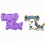 A purple hammerhead-shaped cookie cutter shown next to a decorated example cookie of the same design on a plain white background.