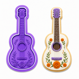 Royal Orchid Lavender guitar cookie cutter and embosser displayed beside a decorated sugar cookie featuring a classic acoustic guitar adorned with vibrant marigold (cempasúchil) flowers on a white background.