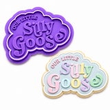 Our Little Silly Goose Cookie Cutter & Embosser Stamp Set displayed beside a hand-decorated sugar cookie featuring soft pastel cotton candy-colored lettering, a light blue icing background, and a white piped border on a clean white background.
