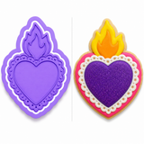 Lavender Sacred Heart cookie cutter with matching embosser displayed beside a decorated sugar cookie featuring a purple heart, golden flame, and pink beaded border.