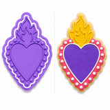 Sacred Heart cookie cutter with matching embosser displayed beside a decorated sugar cookie featuring a purple heart with a lace border and golden flame.