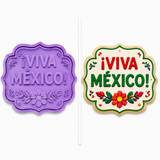 Decorated ¡Viva México! plaque sugar cookie with bold red and green lettering and colorful floral decorations displayed beside a lavender two-piece plaque cookie cutter and embosser.