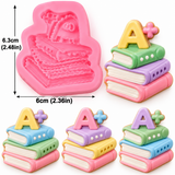 ink silicone fondant mold featuring three stacked schoolbooks topped with an A+ symbol, measuring 2.48 inches tall and 2.36 inches wide, with detailed book covers and layered pages.
