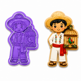 Royal Orchid Lavender Campesino with Birdcage Cookie Cutter & Embosser shown beside a decorated sugar cookie featuring a traditional Mexican campesino wearing a straw sombrero, embroidered white outfit, red sash, and holding a decorative birdcage with a colorful songbird.