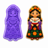 Royal Orchid Lavender Marigold Flower Girl cookie cutter and embosser displayed beside a decorated sugar cookie featuring a traditional Mexican girl wearing a marigold flower crown, embroidered blouse, purple shawl, and black floral skirt on a white background.