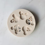 Round white silicone mold featuring four mouse-ear designs with decorative bows, shown with approximately one-inch measurement guides. Ideal for mouse-themed birthday and baby shower cake decorations.
