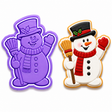 Royal Orchid Lavender Snowman with Broom Cookie Cutter & Embosser Two-Piece Set displayed beside a decorated snowman sugar cookie wearing a black top hat, red scarf, and holding a broom on a white background